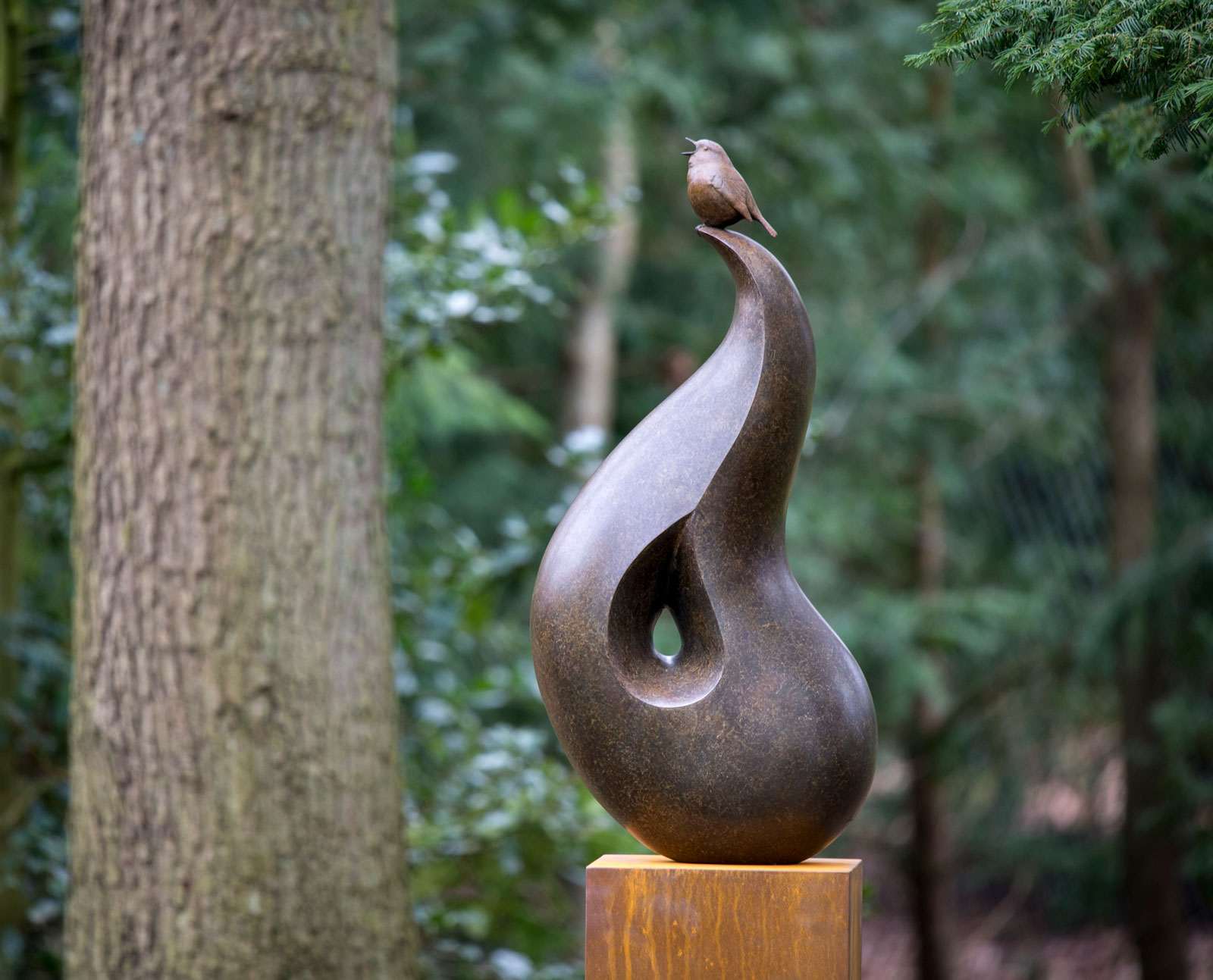 Bronze sculpture of a singing Robin bird perched on top of a smooth abstract shape