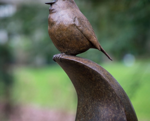 Bronze sculpture of a singing Robin bird perched on top of a smooth abstract shape