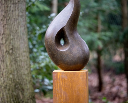 Bronze sculpture of a singing Robin bird perched on top of a smooth abstract shape